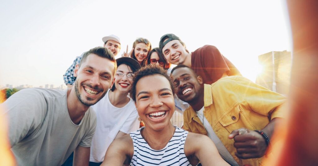 A diverse group of friends taking a joyful selfie outdoors during sunset.