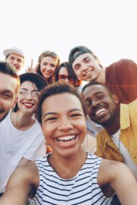 A diverse group of friends taking a joyful selfie outdoors during sunset.